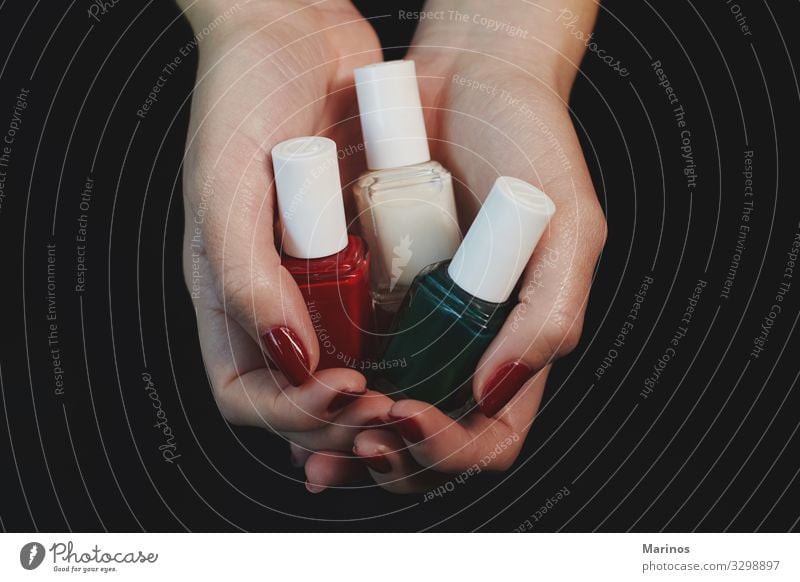 Polnische Flaschen in Frauenhänden. schön Maniküre Behandlung Spa Mensch Erwachsene Hand Finger rot Farbe nageln Pflege Salon Trimmen Beautyfotografie Nägel