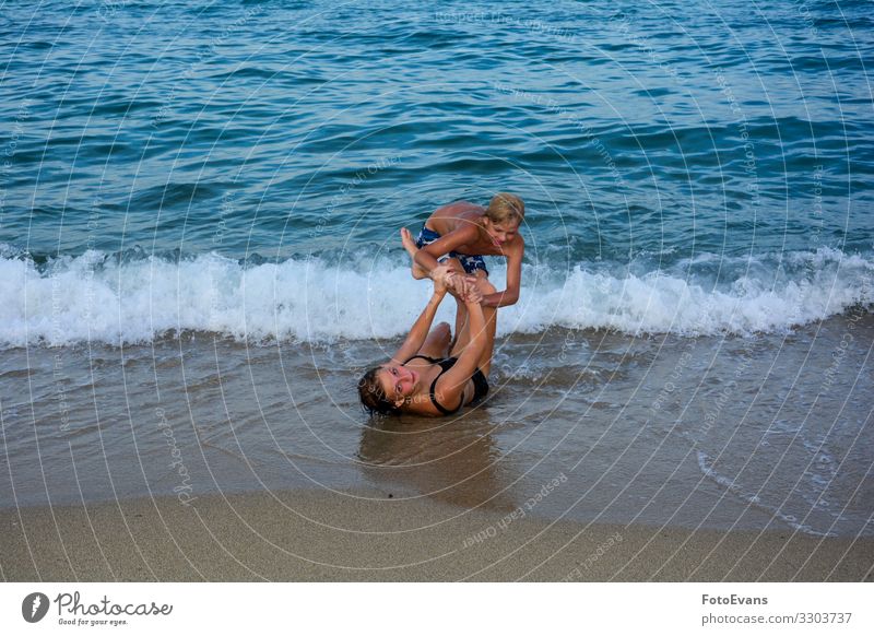 Zwei lustige Kinder spielen gemeinsam an einem Strand vor einer Meereswelle zwei Geschwister Bruder und Schwester Sandstrand MEER Menschen kämpfen Spaß Freude