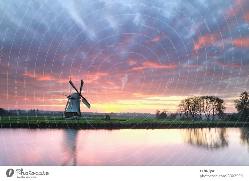 dramatischer lila Sonnenaufgang über einer Windmühle am Fluss holländisch Niederlande weiß Kanal Wasser Morgendämmerung Horizont Himmel Cloud Wolkenlandschaft