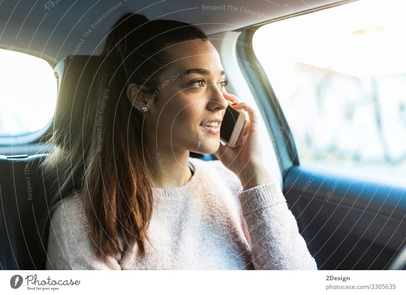 Junge schöne Frau mit Pferdeschwanz telefoniert auf dem Rücksitz eines Autos PKW sprechend Handy Business hübsch urban gefesselt Mädchen Menschen niedlich