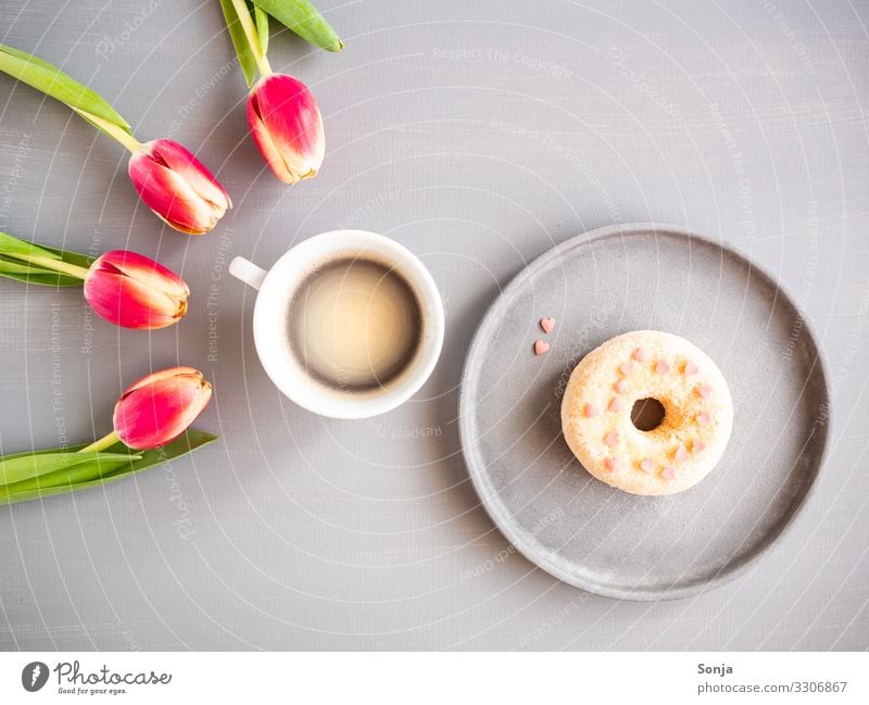 Rosa Tulpen mit einer Tasse Kaffee und einem Donat Lebensmittel Teigwaren Backwaren donat Ernährung Frühstück Kaffeetrinken Getränk Heißgetränk Teller Lifestyle
