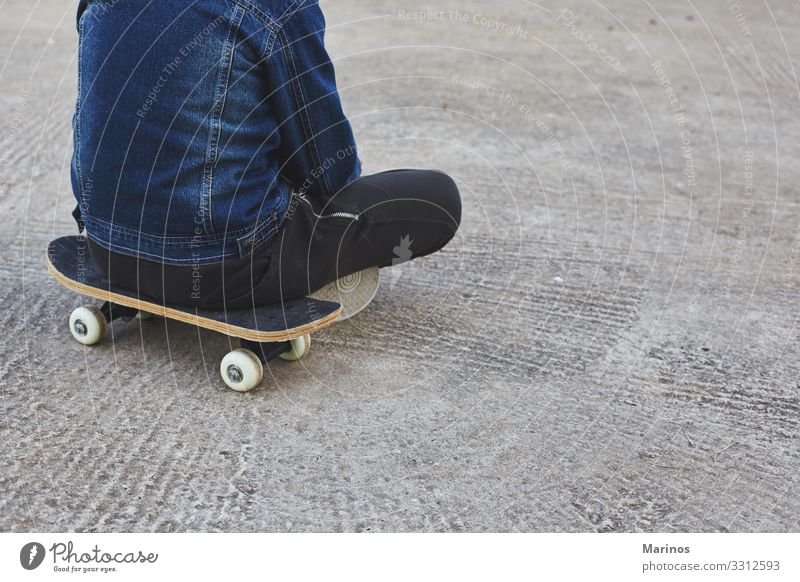 Kinderskateboardfahrer, der auf seinem Skateboard sitzt. Lifestyle Freude Sport Mensch Junge Jugendliche Park Straße Jeanshose Skateboarding Schlittschuh