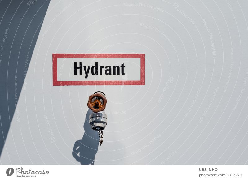 Hydrant vor hellem Hintergrund mit Schild Industrie Metall einfach grau rot weiß Sicherheit Schutz Rettung Anschluss Schriftzeichen Feuerwehr Brandschutz