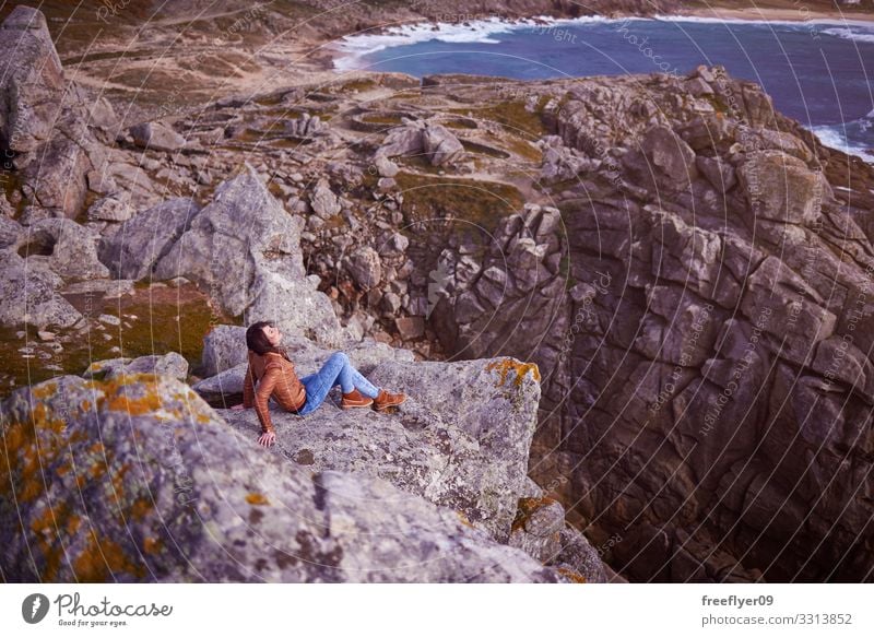Frau sitzt auf einer Klippe in der Nähe von Baroña Castro in Galizien Barona keltisch Galicia Spanien wandern Tourismus Natur Küstenlinie Steine Landschaft jung