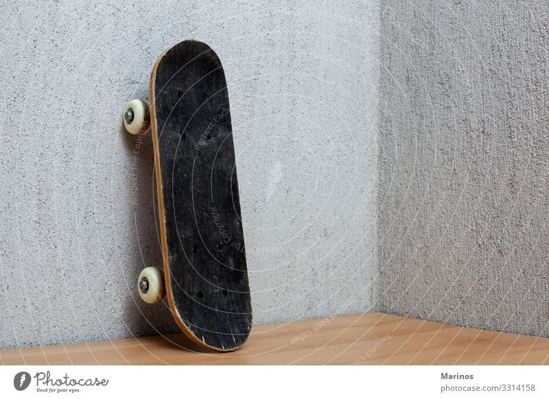 Skateboard, das an einer Wand steht. Lifestyle Sport Junge Straße Schuhe Turnschuh stehen lang grau schwarz Schlittschuh Holzplatte Schlittschuhlaufen