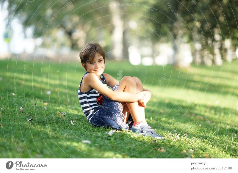Kleines Mädchen, acht Jahre alt, sitzt auf dem Rasen im Freien. Stil Freude Glück schön Gesicht Spielen Ferien & Urlaub & Reisen Freiheit Sommer Kind Schulkind