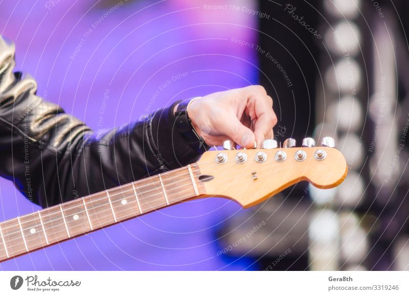 männlicher Handmusiker stimmt Gitarre aus nächster Nähe Spielen Musik Mann Erwachsene Finger Konzert Musiker Felsen Bekleidung Jacke schwarz Farbe Hintergrund