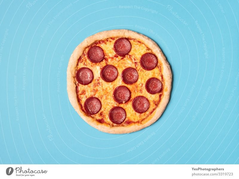 Pizzasalami auf blauem Hintergrund. Ganze Pizza mit Peperoni. Lebensmittel Teigwaren Backwaren Ernährung Mittagessen Abendessen Fastfood Fingerfood