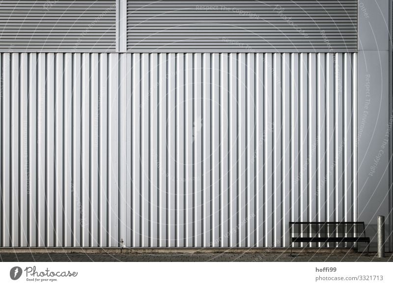 einsame Bank mit Ascher vor Wellblech Fassade Haus Industrieanlage Architektur Mauer Wand Aschenbecher Metall Stahl Linie sitzen warten ästhetisch einfach