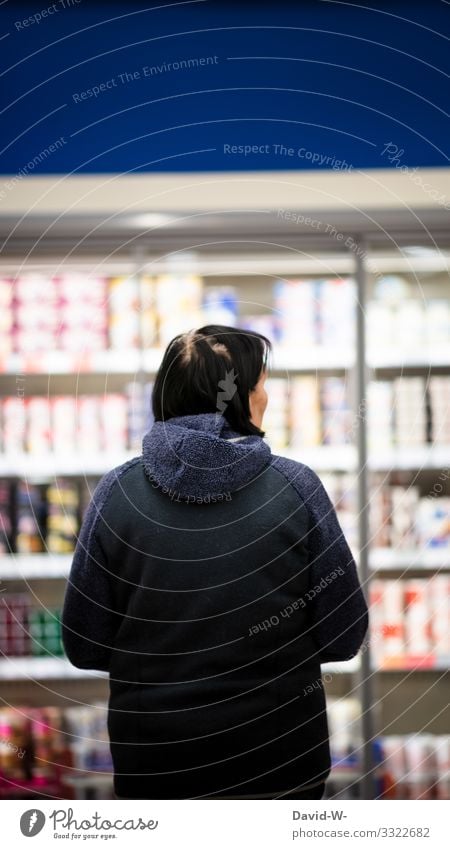 eine Frau steht in einem Lebensmittelladen vor einem Kühlregal Einkaufswagen einkaufen Supermarkt Farbfoto Konsum Ladengeschäft Mensch verbraucher legen