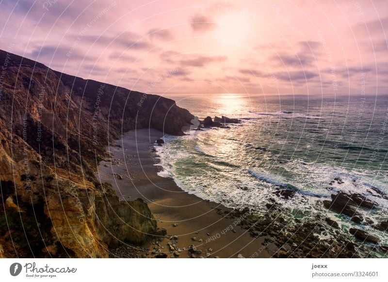 Steile Küste mit felsigem Strand und Brandung vor rosa Wolkenhimmel Meer Wellen Natur Landschaft Himmel Schönes Wetter Felsen gigantisch groß maritim braun weiß