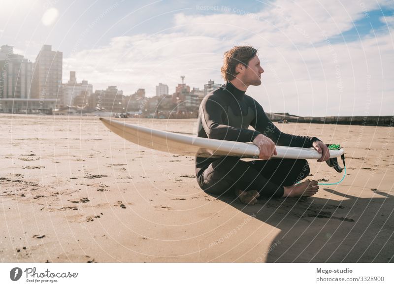 Surfer, der mit einem Surfbrett am Sandstrand sitzt. Lifestyle Glück Erholung Freizeit & Hobby Abenteuer Strand Meer Wellen Sport Wassersport Mensch maskulin