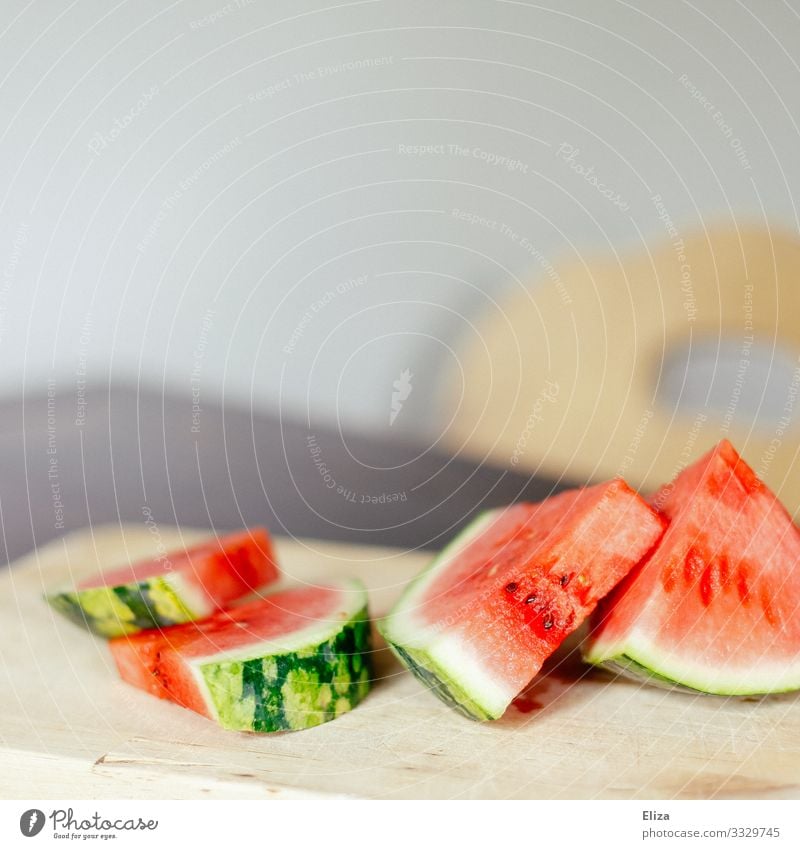 Aufgeschnittene Wassermelone auf einem Schneidebrett aus Holz auf einem Tisch Lebensmittel Frucht lecker aufgeschnitten Holzbrett süß fruchtig frisch sommerlich