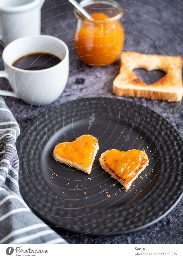 Frühstück mit Toastbrot in Herzform und Aprikosenmarmelade Lebensmittel Brot Marmelade Ernährung Kaffeetrinken Getränk Heißgetränk Teller Tasse Glas Tisch