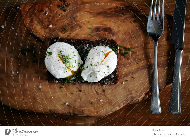 Zwei pochierte Eier auf Schwarzbrot Lebensmittel Brot Körnerbrot Gabel Messer Würzig Ernährung Frühstück Abendessen Bioprodukte Slowfood Deutsche Küche Besteck