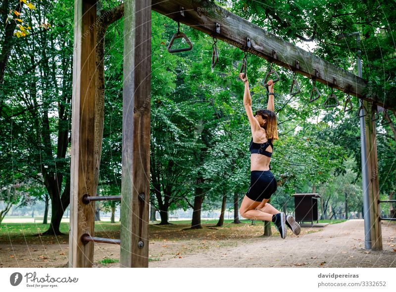 Frau macht Affenübungen auf Ringen Lifestyle Körper Sport Mensch Erwachsene Baum Park Wege & Pfade Turnschuh Fitness dünn stark Kraft anstrengen Sportlerin