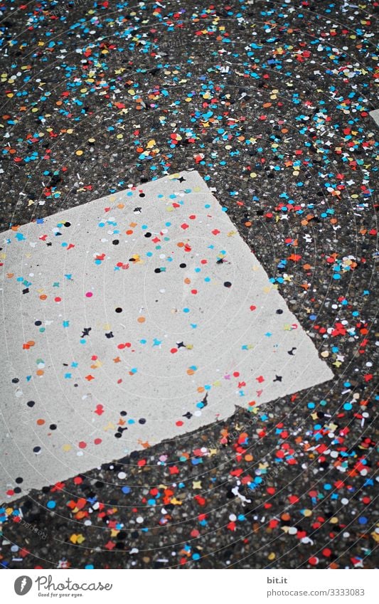 Viel, buntes Konfetti liegt verteilt bei Fasnacht, Karneval, Fasching, Fest, Feier auf dem grauen Boden der Straße mit Markierung und sorgt für Müll und Schmutz.
