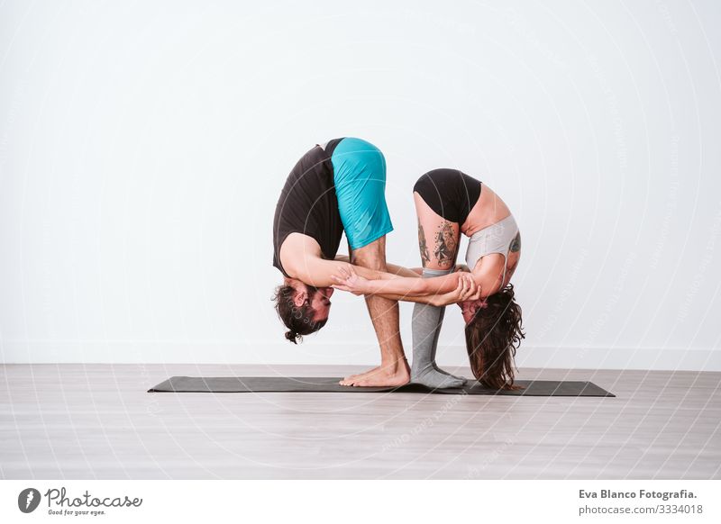 junges Paar, das in einem weißen Studio oder einer Sporthalle Akro-Yoga praktiziert. Gesunder Lebensstil im Innenbereich Gesundheit Mann Kraft Mensch