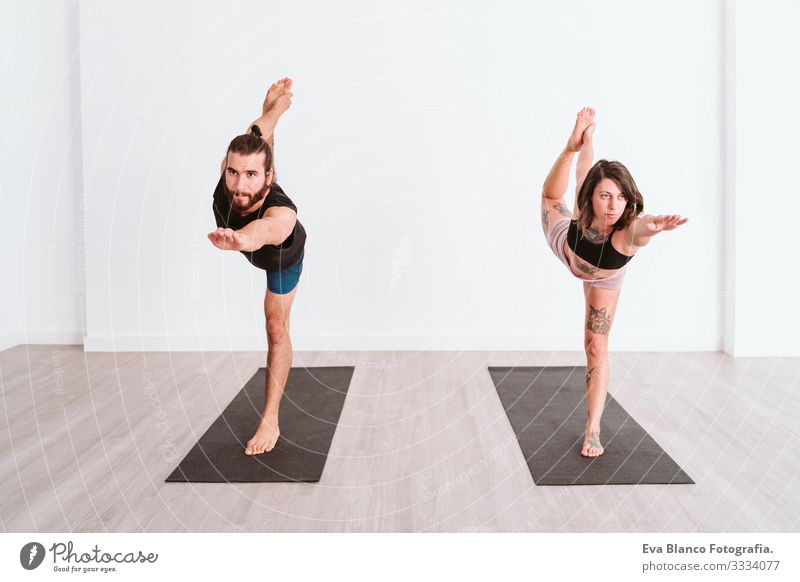 junger Mann und Frau, die in der Sporthalle Yoga-Sport betreiben. Gesunder Lebensstil Junge Gesundheit Lifestyle Innenaufnahme Studioaufnahme weiß hispanisch