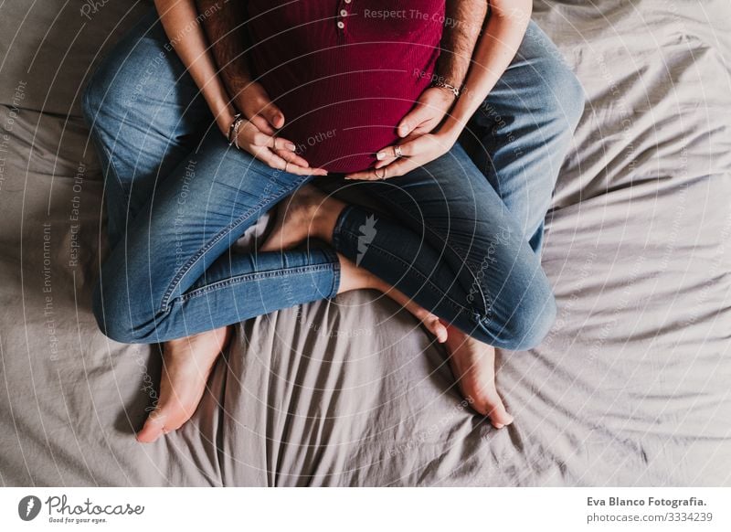 junges Paar zu Hause beim Umarmen. Glückliche schwangere Frau lächelt. Ansicht von oben Liebe Eltern erwartend heimwärts Sofa Küssen Elternschaft Mutterschaft