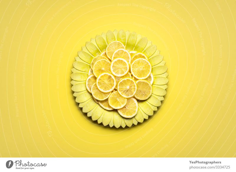 Zitronenscheiben auf gelber blütenförmiger Platte. Zitrusfrüchte in Scheiben Lebensmittel Frucht Frühstück Teller Gesunde Ernährung hell obere Ansicht ganz gelb