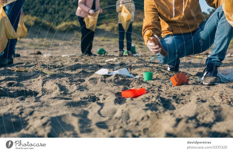 Junger Mann putzt den Strand Arbeit & Erwerbstätigkeit Mensch Erwachsene Familie & Verwandtschaft Hand Menschengruppe Umwelt Sand Kunststoff dreckig Sauberkeit