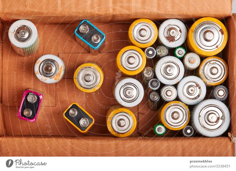 Entladene Batterien in einem Karton. Sammeln von gebrauchten Batterien zum Recycling. Abfallentsorgung und Recycling. Kopierplatz für Text Umwelt alt grün