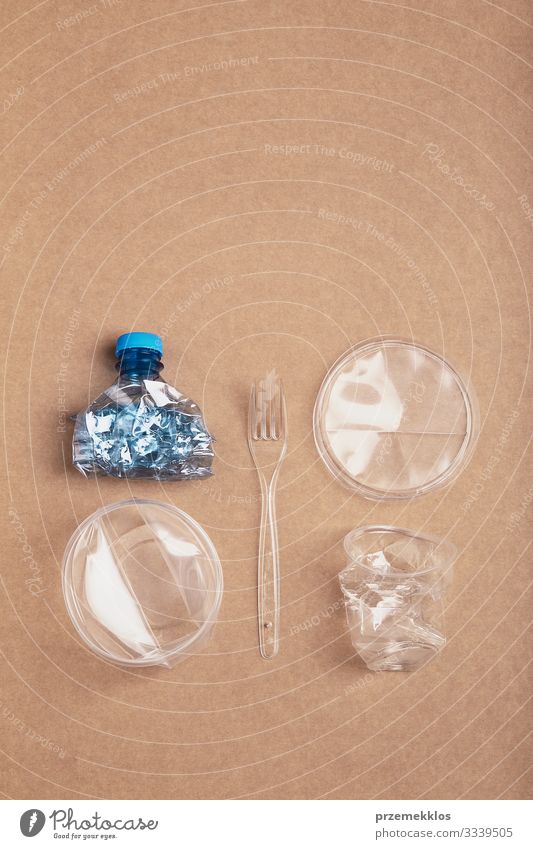Zerquetschte Plastikflasche, Schachtel, Becher und Gabel über Karton Flasche sparen Umwelt Container Verpackung Kunststoffverpackung Kristalle blau