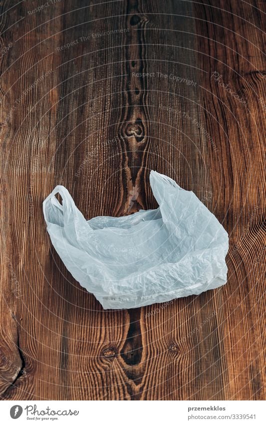 Weiße, leere Plastiktüte, die über einem Holzuntergrund schwebt kaufen Umwelt Container Verpackung Paket Kunststoffverpackung weiß Umweltverschmutzung