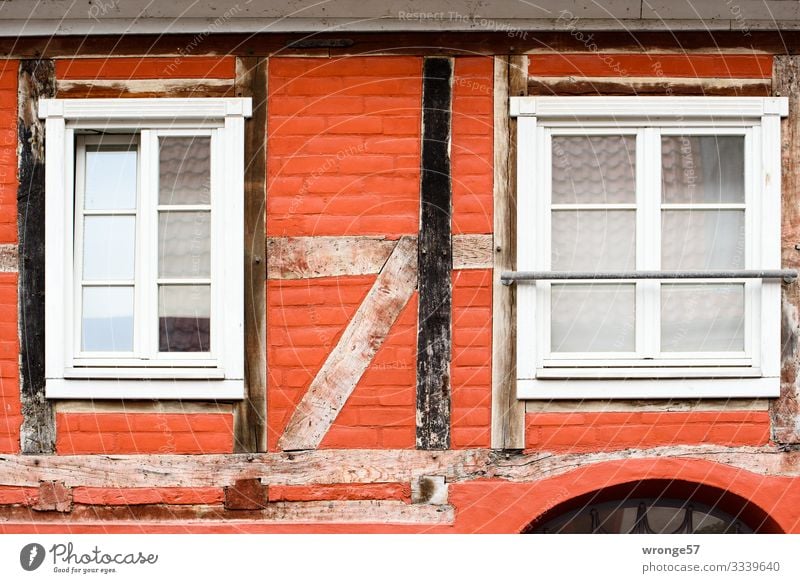 Nahaufnahme der Fassade eines rotgestrichenen Fachwerkhauses mit zwei Fenstern und gut sichtbarer Balkenkonstruktion Fachwerkfassade Außenaufnahme Haus