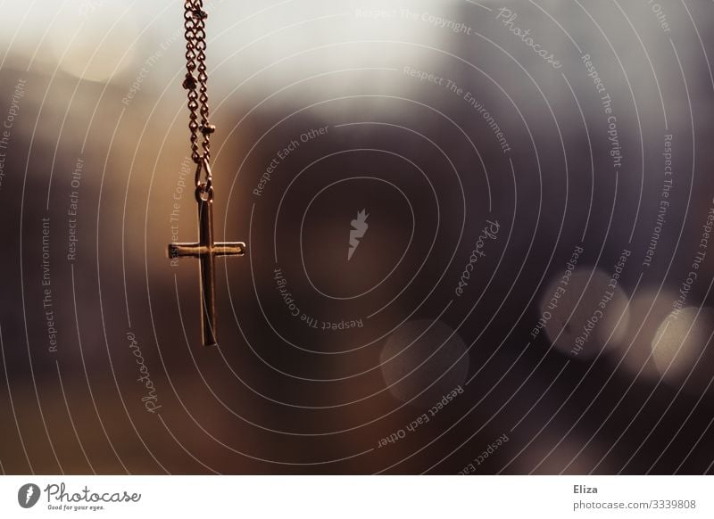 Ein Goldenes Kreuz Kruzifix hängt an einer Kette vor unscharfem Hintergrund in der Kirche Glaube gold Christliches Kreuz Religion & Glaube Christentum