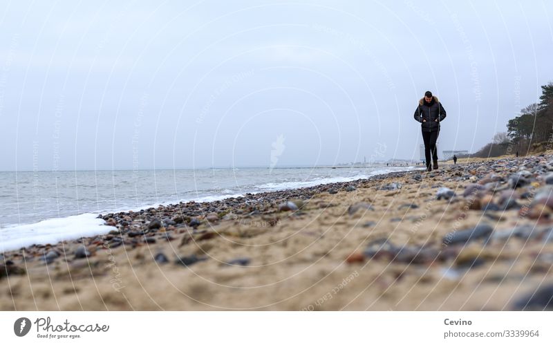 Junger Mann spaziert am Strand Spaziergang Ostsee junger Mann Einsam Einsamkeit Gedanken Urlaub Wellen Steine Sand Wanderung gedankenverloren grübeln
