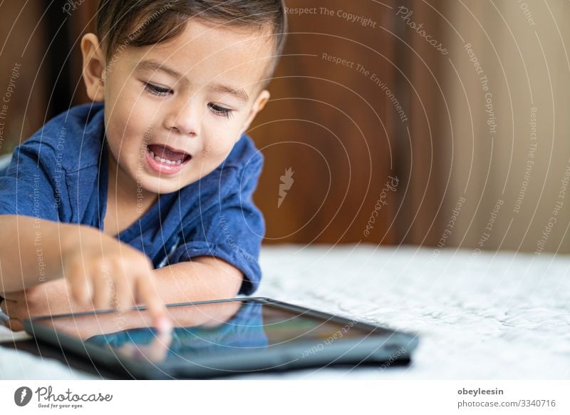 süßer junger Mischlingsjunge, der mit einem elektronischen Gerät spielt Freude Glück Spielen lesen Sommer Garten Schlafzimmer Kind Computer