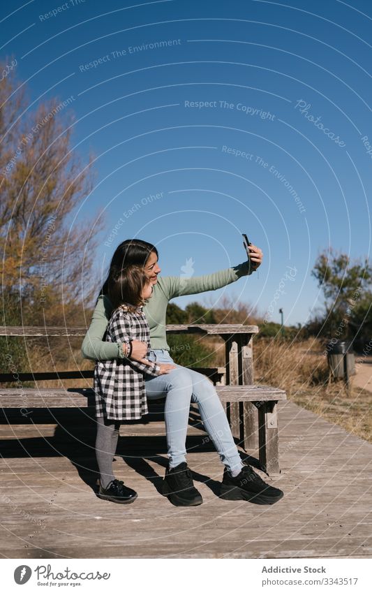 Glückliche ethnische Mutter, die mit ihrem Kind Selbsthilfe nimmt Selfie Mädchen Telefon benutzend Foto Lächeln Umarmung Zusammensein sich[Akk] entspannen Natur