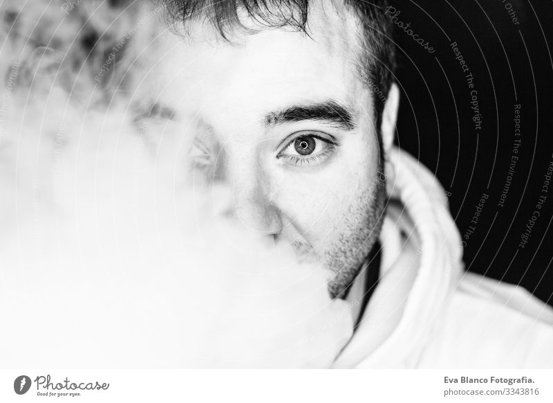 Porträt eines jungen Mannes beim Rauchen, Studioaufnahmen, schwarz-weiß, Nahaufnahme. Led-Ringreflexion in den Augen Kopf dunkel Mensch Zigarette schlecht