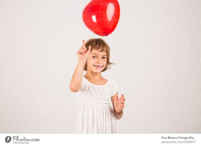 Kind, das im Studio mit einem roten Ballon spielt. Spaß, Lebensstil. weißer Hintergrund Porträt Freude niedlich Lifestyle-Glück heiter schön klein Behaarung