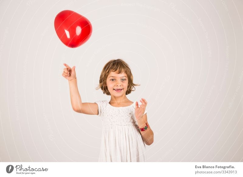 Kind, das im Studio mit einem roten Ballon spielt. Spaß, Lebensstil, weißer Hintergrund Porträt Freude niedlich Lifestyle-Glück heiter schön klein Behaarung