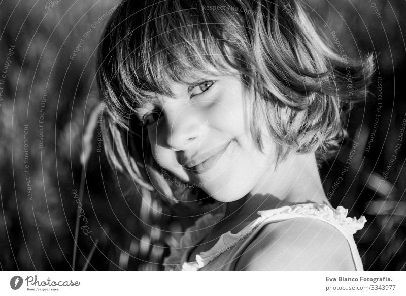 Porträt im Freien bei Sonnenuntergang eines schönen Mädchens inmitten der Blumen. Schwarz-Weiß-Fotografie. Unschuld und Lebensweise der Kinder. Sommer Lächeln