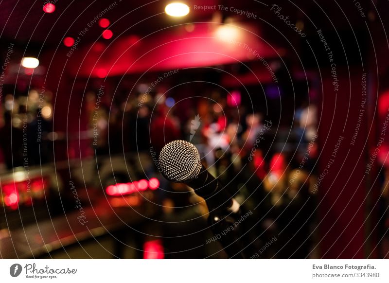 Mikrophon auf einer Komödien-Ständerbühne mit farbenfrohem Bokeh , kontrastreichem Bild. Mikrofon Party Nacht Club Mensch Menge Weihnachten & Advent rot