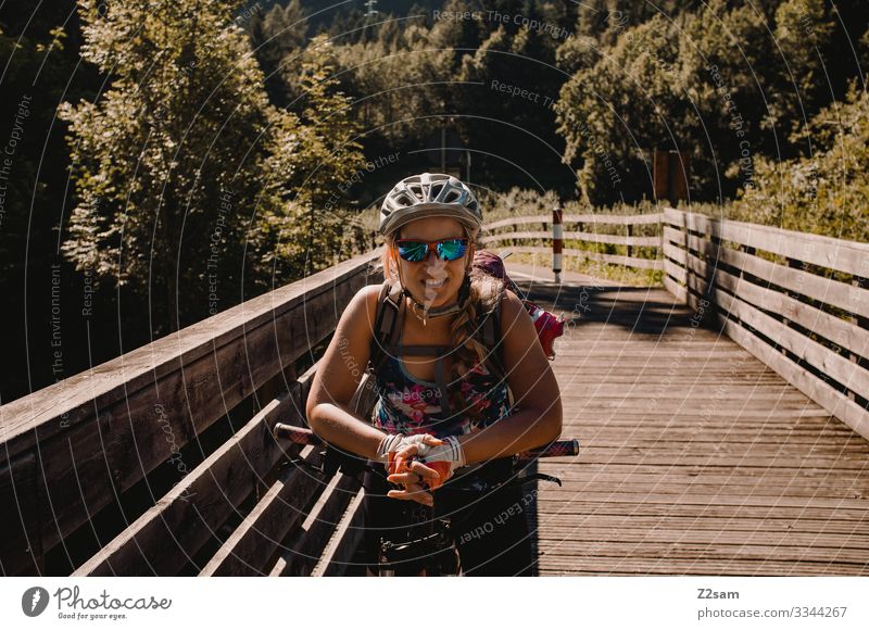 Junge Frau mit dem Mountainbike in Italien alpenüberquerung gardasee mountainbike mtb transalp junge frau lachen helm sonnenbrille fahrradweg sommer sport natur
