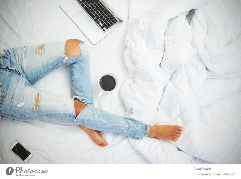 Junge Frau beim Kaffeetrinken zu Hause in ihrem Bett - Draufsicht schön Leben Erholung lesen Schlafzimmer Arbeit & Erwerbstätigkeit Arbeitsplatz Telefon PDA