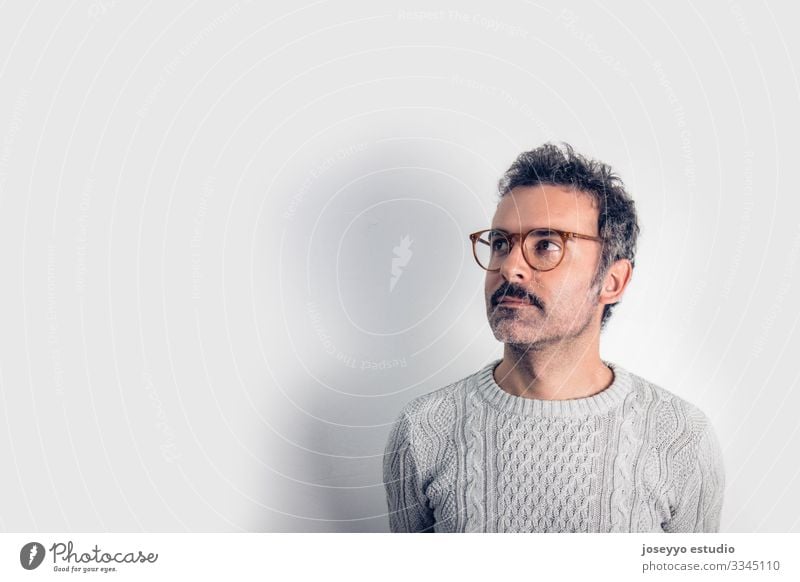 Porträt eines gut aussehenden und braun denkenden Mannes mit Schnurrbart, Brille und grauem Pullover. Grauer Hintergrund. Platz zum Kopieren Erwachsener Waffen