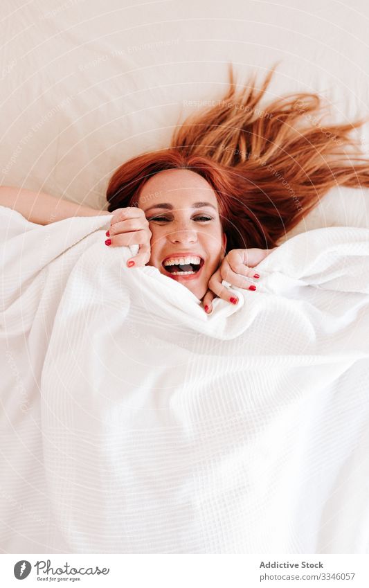 Positive Dame versteckt sich zu Hause unter einer Decke Frau Lügen Bett versteckend Morgen Sitzen Deckung Spaß unten sich[Akk] entspannen ruhen Lächeln genießen