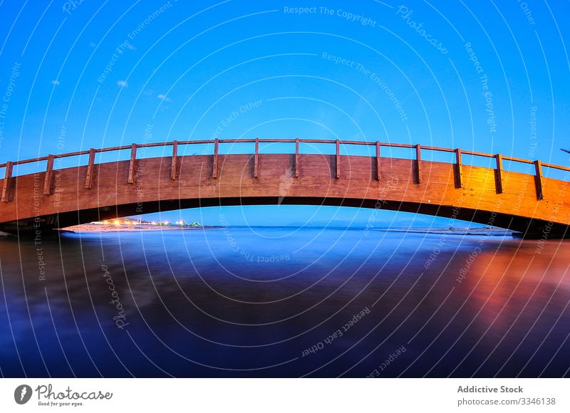 Holzbrücke, die sich im Bogen über eine flache Wasseroberfläche unter blauem Himmel erstreckt Stadtbild Brücke Reflexion & Spiegelung Fluss Architektur reisen