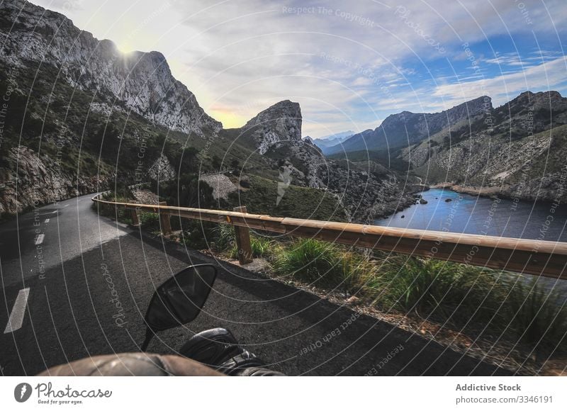 Gesichtsloser Tourist fährt Motorrad auf einer von Bergen umgebenen Straße Mann Mitfahrgelegenheit Berge u. Gebirge reisen Schlucht See Landschaft Ausflug