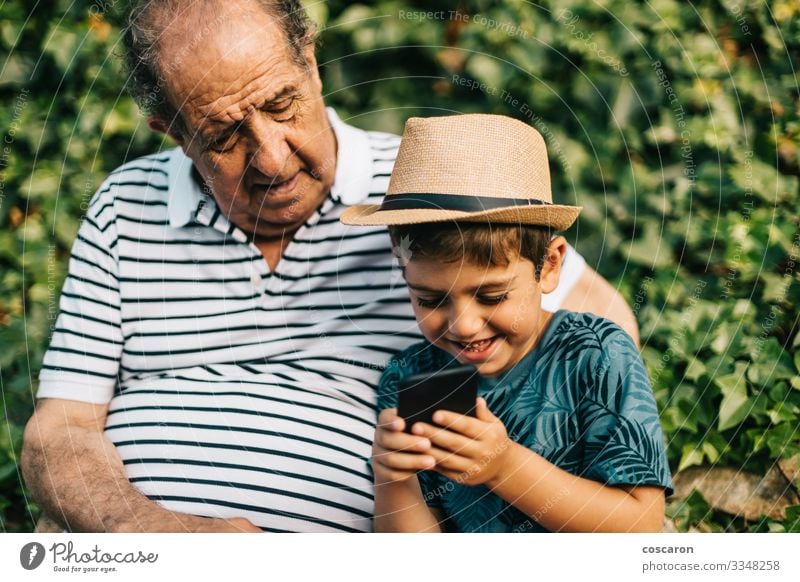 Großvater und Enkel spielen mit einem Mobiltelefon Lifestyle Glück Freizeit & Hobby Spielen Ferien & Urlaub & Reisen Tourismus Sommer Sommerurlaub Kind