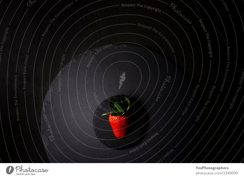 Eine einzelne Erdbeere auf einer schwarzen Granitplatte. Ansicht oben Frucht Dessert Bioprodukte Diät frisch lecker natürlich obere Ansicht Beeren Schwarzblech