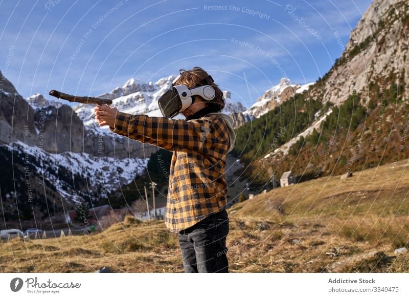Auf Stein stehender Junge mit VR-Brille gegen Berg Natur Tal Berge u. Gebirge virtuell kleben Realität Headset modern Gerät Entertainment erkunden Gelände