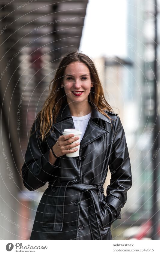 Porträt einer jungen Frau, die eine Kaffeetasse im Freien hält Lifestyle schön Erwachsene Jugendliche Straße Mantel Leder Fröhlichkeit Gefühle Lebensfreude