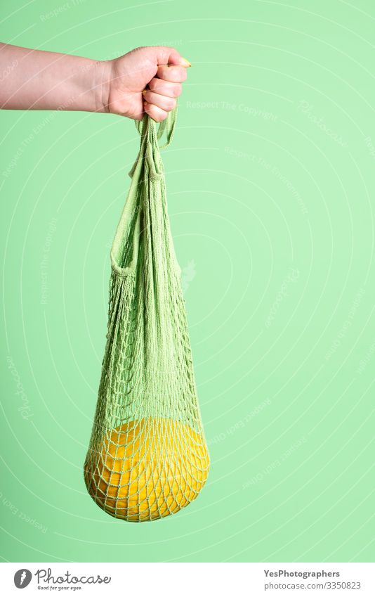 Gelbe Melone in wiederverwendbarer Netz-Einkaufstasche Frucht Dessert Bioprodukte Diät kaufen Gesunde Ernährung feminin Hand grün Früchte kaufen farbenfroh